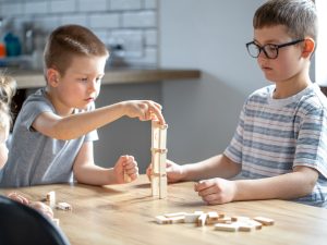 Children play a board game with a wooden turret at home.